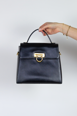 Black leather handbag with gold hardware and top handle and detachable strap